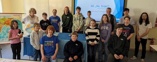 Gruppenfoto von Susanne Menge und 14 Schüler:innen der AG "Na, Erde?" in einem Schulraum