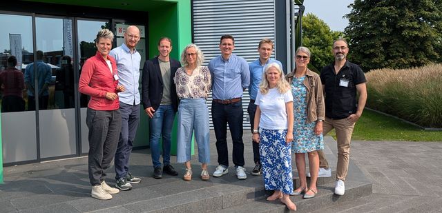 Susanne Menge mit einer Gruppe von Grünen Abgeordneten und Mitarbeitenden der Rügenwalder Mühle vor dem Bürogebäude der Rügen